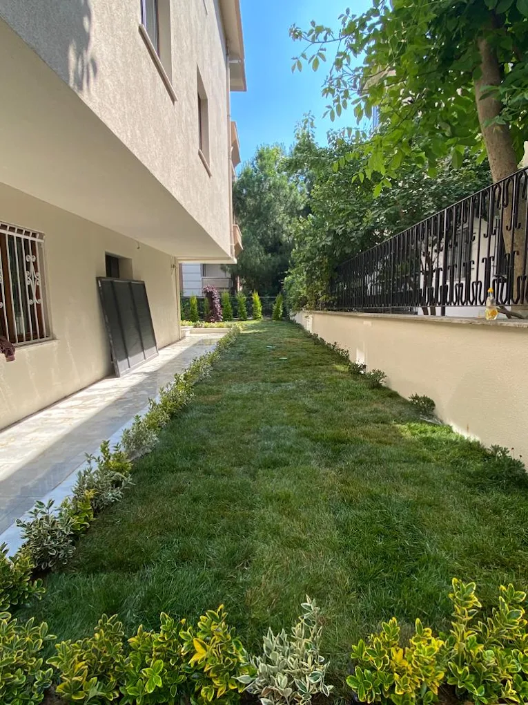 Çim ve çiçeklerle tamamlanmış bakımlı bahçe